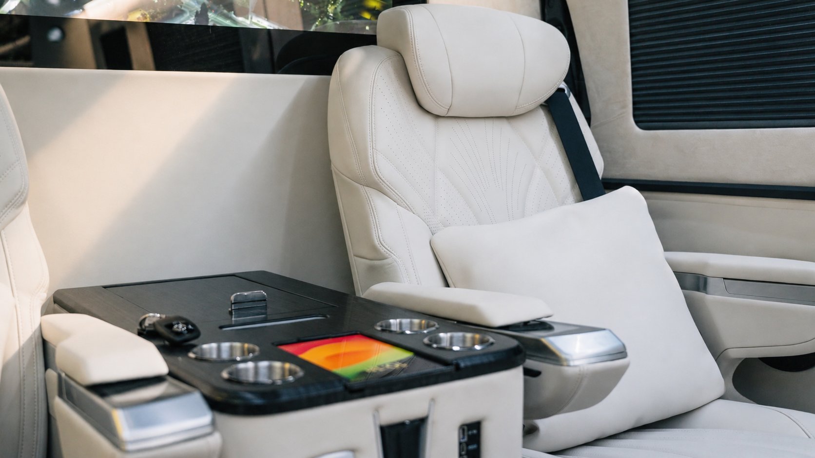 DJ turntable and mixer console set up on a table inside a luxury camper van with white leather seats