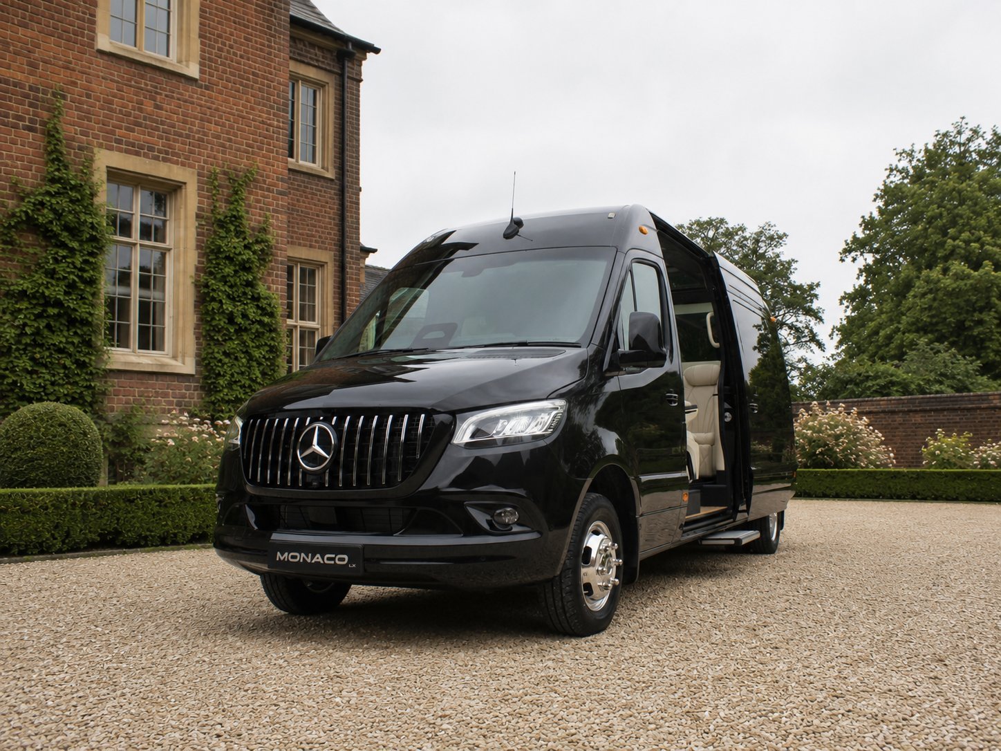 Black Mercedes-Benz luxury van with open doors parked on gravel driveway in front of brick mansion