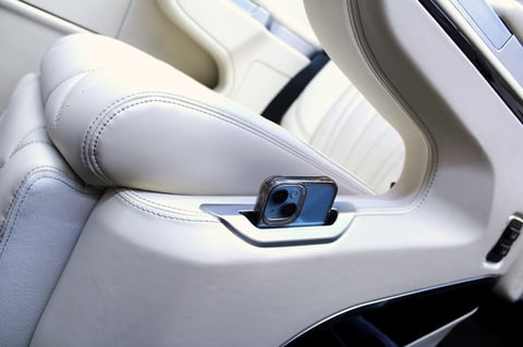 Blue smartphone mounted on white leather car door handle with interior details visible
