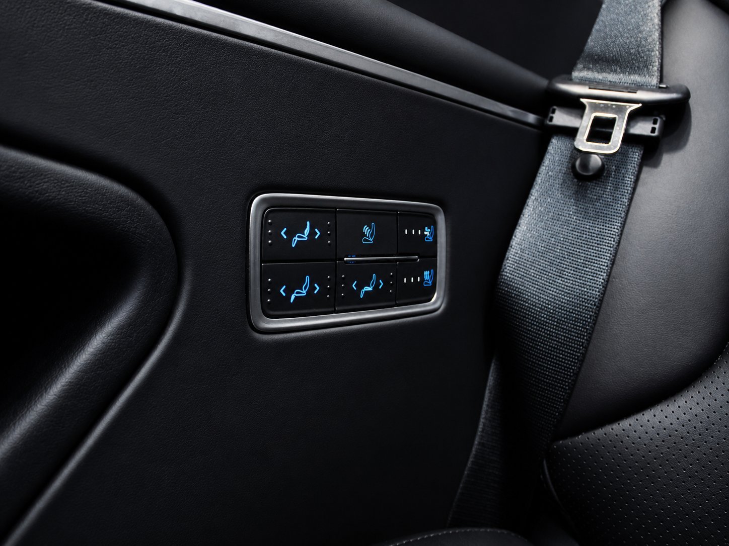 Digital climate control panel with illuminated blue buttons mounted on dark car dashboard interior
