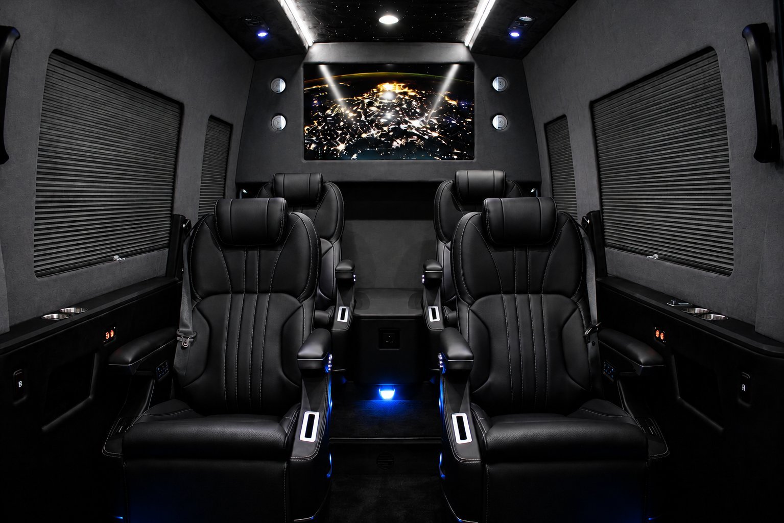 Interior of a luxury vehicle with dual black leather captain seats, modern lighting, and a roof-mounted display screen