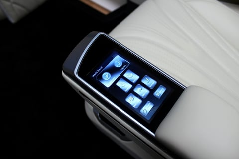 Smartwatch with rectangular touchscreen displaying app icons, placed on white wrist band against black background