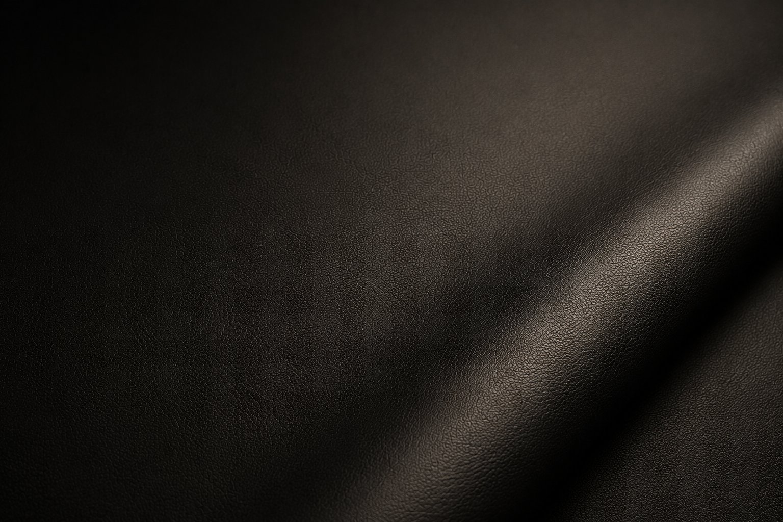 Close-up of dark textured leather or fabric with diagonal light reflection creating a gradient shadow effect